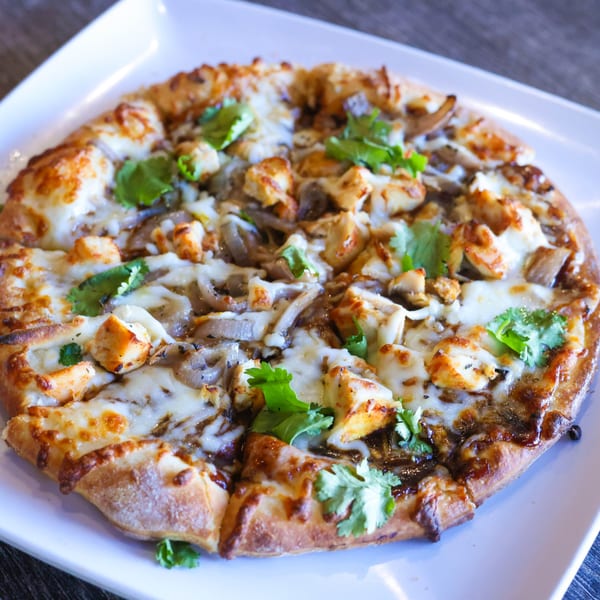Milano's Pizzeria's BBQ chicken pizza, topped with melted cheese, chicken, onions, and cilantro.