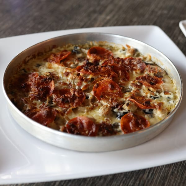 A Milano's Pizzeria deep dish pizza with pepperoni, cheese, and mushrooms in a metal pan.